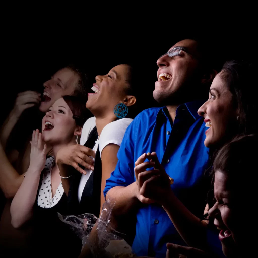 Women and men with different ethnicities laughing at joke from a comedian for hire.