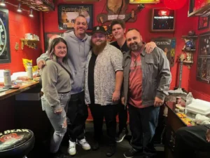 Pictured here is The Comedian Company president Jason Douglas (in the gray jacket) sharing a moment with Pete Davidson in a gray hoodie. Other comedians for hire in a red backstage room.